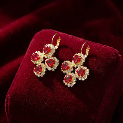 Luxe gouden oorhangers met klavertje vier van rode Swarovski hartjes